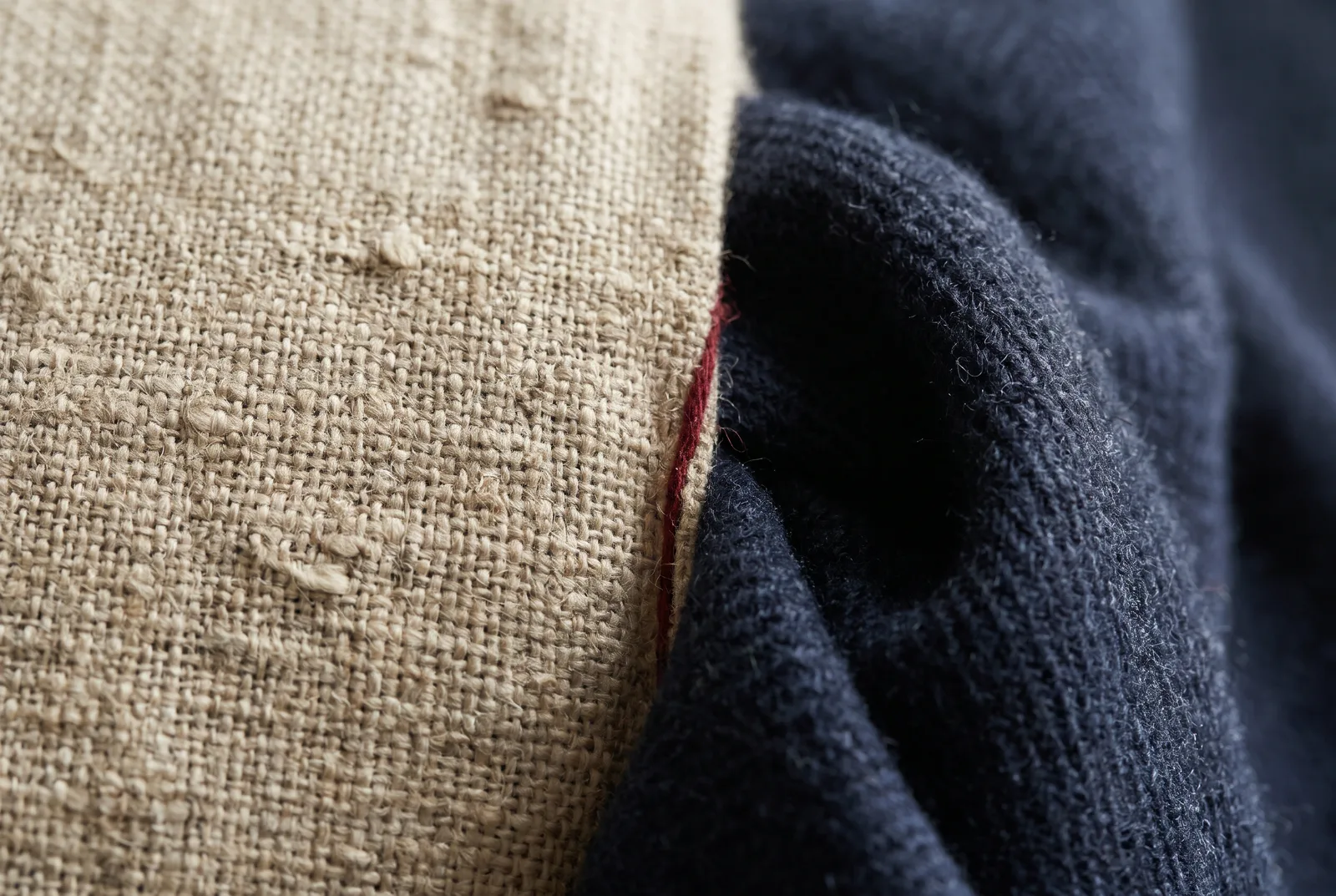Close-up of a natural linen plain weave beside a fold of indigo wool twill
